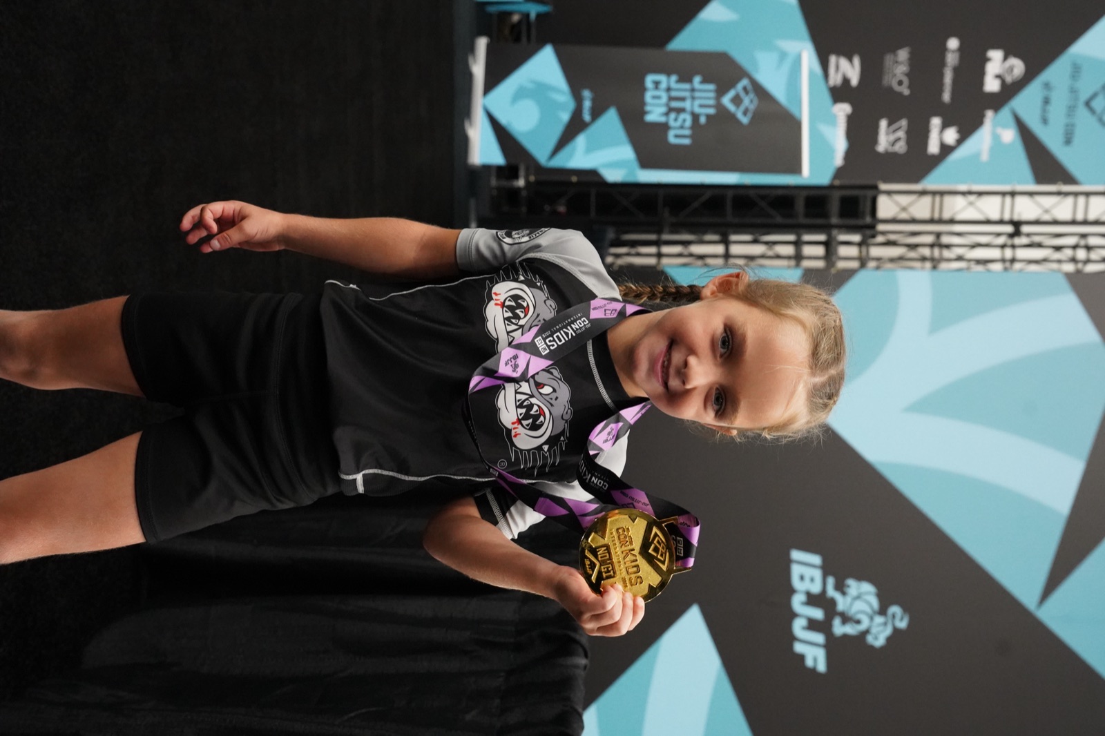 A young student with her gold medal at IBJJF Jiu-Jitsu Con Kids, no gi